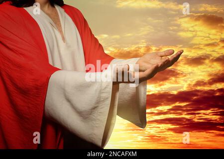 Jesus Christus streckte seine Hände aus und betete bei Sonnenuntergang Stockfoto