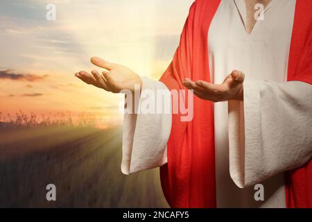 Jesus Christus streckte seine Hände aus und betete bei Sonnenuntergang Stockfoto