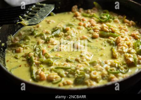 Garnelen, Gemüse und Sahne in einer Bratpfanne. Zubereitung von Shrimps-Spaghetti-Sauce mit Gewürzen. Stockfoto