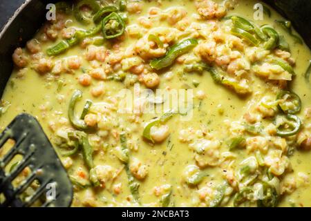 Garnelen, Gemüse und Sahne in einer Bratpfanne. Zubereitung von Shrimps-Spaghetti-Sauce mit Gewürzen. Stockfoto