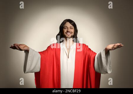 Jesus Christus streckt seine Hände auf beigefarbenem Hintergrund aus Stockfoto