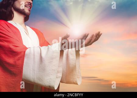 Jesus Christus streckte seine Hände aus und betete bei Sonnenuntergang Stockfoto
