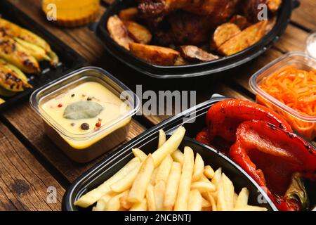 Kunststoffbehälter mit verschiedenen Schalen auf Holztisch, Nahaufnahme. Lebensmittellieferservice Stockfoto