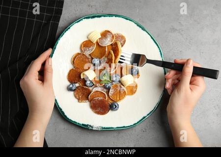 Eine Frau isst Cornflakes-Pfannkuchen an einem hellgrauen Tisch, Draufsicht Stockfoto