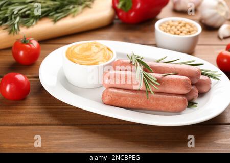 Köstliche vegetarische Würstchen mit Rosmarin und Sauce auf einem Holztisch Stockfoto