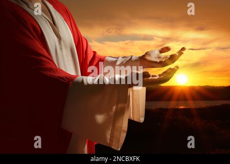 Jesus Christus streckte seine Hände aus und betete bei Sonnenuntergang Stockfoto