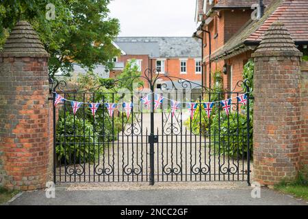 Viktorianisches englisches Landhaus mit Auffahrt und schwarzeisernen Toren, dekoriert mit Union Jack Bunting. Buckinghamshire, England, Großbritannien Stockfoto