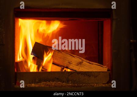 Nahaufnahme von Holzstämmen, die in einem Holzofen brennen und Wärme und Wärme abgeben. Stockfoto