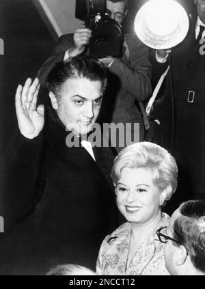 Italian movie director Federico Fellini waves to cheering crowd as he and his actress-wife Guilietta Masina, arrive at a fashionable Rome, Italy, movie theater on Feb. 13, 1963, to attend the premiere of Fellini’s latest film, “8 ½”, starring Italian actor Marcello Mastroianni and actress Claudia Cardinale. (AP Photo)