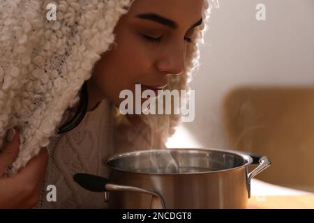 Eine Frau mit Karomuster, die drinnen über dem Saucetopf inhaliert Stockfoto