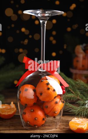 Weihnachtskomposition mit tangerinen Pomanderkugeln im Weinglas auf Holztisch Stockfoto