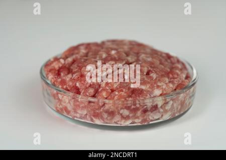 Petrischale mit rohem Hackfleisch auf weißem Tisch, Nahaufnahme Stockfoto