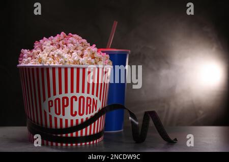 Köstliches Popcorn, Getränk und Klebeband auf dem Tisch. Platz für Text Stockfoto