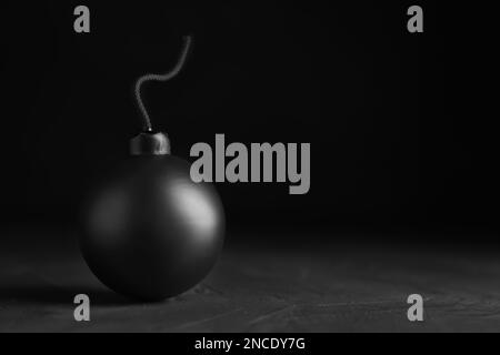 Kugelförmige Bombe mit brennender Sicherung auf schwarzem Hintergrund. Platz für Text Stockfoto