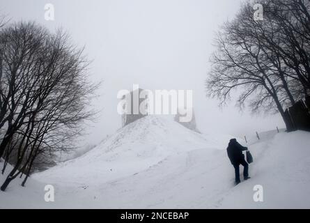 A man makes his way up a hill during a fog with the ruins of a medieval castle in the background, in the town of Novogrudok, 150 km (93 miles) west of Minsk, Belarus, Saturday, Jan. 8, 2011. (AP Photo/Sergei Grits)
