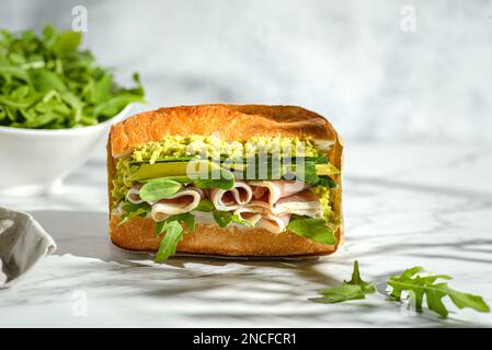Avocado und parma Sandwich. Baguette-Sandwich in handwerklicher Verpackung für die Lieferung Stockfoto