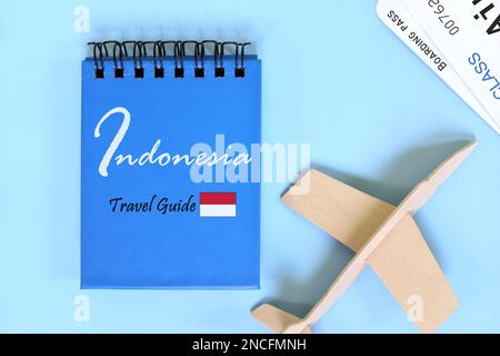 Indonesien Reiseführer geschrieben auf blauem Notizblock mit Flagge und Holzflugzeug. Festliche Flachlagenkomposition. Stockfoto