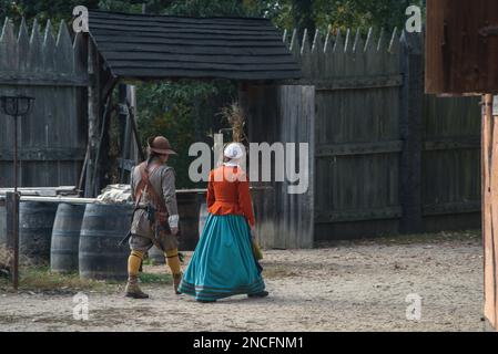 Ein Mann und eine Frau in historischen Kleidern, die über die Nachbildung der Jamestown Siedlung in Jamestown, Virginia, USA laufen Stockfoto