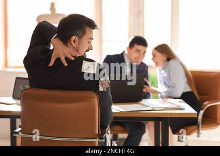 Haftnotiz und Papierfisch auf dem Rücken eines jungen Mannes im Amt. Feier zum 1. April Stockfoto