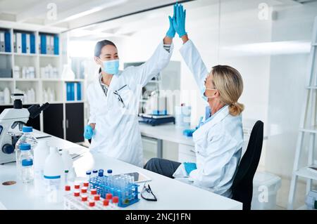 Die Wissenschaft macht in der Welt positive und bemerkenswerte Fortschritte. Zwei Wissenschaftler, die sich gegenseitig in einem Labor einen High Five geben. Stockfoto