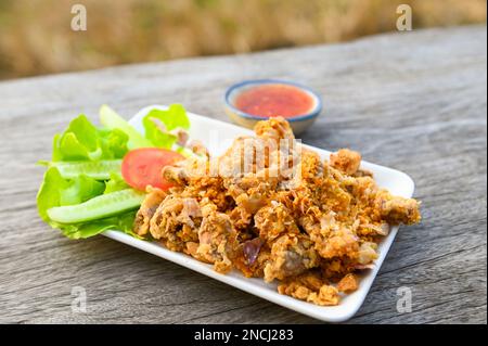 Gebratener Schweinedarm mit Knoblauch und Sauce auf dem Teller - gebratene Schweineabfälle, thailändische Speisen oder Snacks Stockfoto