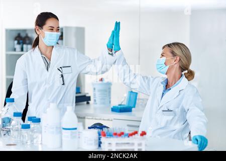 Dann machen Sie gemeinsam medizinische Geschichte. Zwei Wissenschaftler, die sich gegenseitig in einem Labor einen High Five geben. Stockfoto