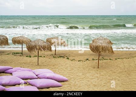 Schlechtes Wetter. Einsamer Strand. Leere Sonnenliegen am stürmischen Meer Stockfoto