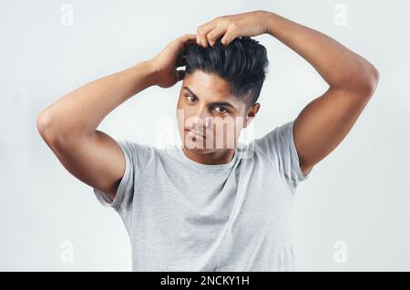 Ich muss sicher gehen, dass ich gut aussehe. Studiofoto eines jungen Mannes, der seine Finger durch sein Haar steckt. Stockfoto