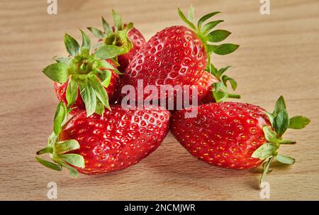 Frisch ausgewählte Erdbeeren, gestapelt auf einer Rutsche auf Holzhintergrund Stockfoto
