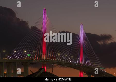 Die New Gerald Desmond Bridge, die nach Westen blickt, wird in der Abenddämmerung im Hafen von Long Beach, Kalifornien, mit St. Farbschema zum Valentinstag. Stockfoto