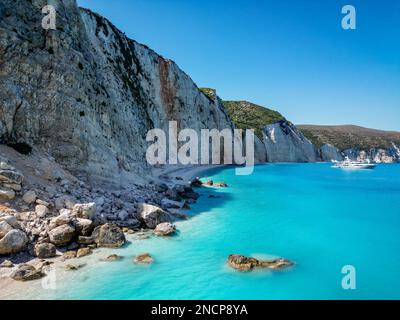 4K Drohnenaufnahme des Kalksteinhügels am Fteri Beach, Kefalonia, Cephalonia, Griechenland mit einer großen Yacht in der Ferne Stockfoto