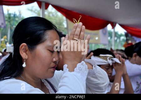 Bali, Indonesien - 3. März 2015 : Eine Hindu-Frau betet mit einer Blume zwischen den Fingerspitzen, Bali, Indonesien Stockfoto