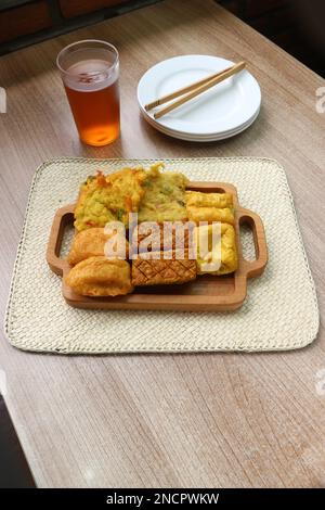 Gebratener Tofu, gebratener Tempeh, gebratene Kartoffelkuchen und Cornflakes auf einem Holztablett Stockfoto