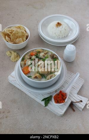 Eine Schüssel Rindfleisch und Gemüsesuppe in Kokosmilchsauce serviert mit Reis und Crackern Stockfoto