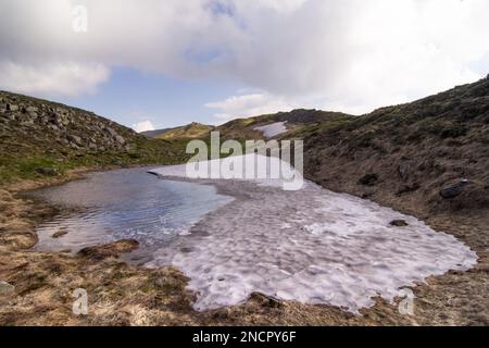 Schmelzende Eispfütze auf einem Landschaftsfoto der Frühlingsberge Stockfoto