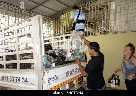 Freiwillige in Phnom Penh, Kambodscha sammeln Recycling und transportieren es zur Kokosnussschule, die aus Abfallmaterialien gebaut wird. Stockfoto