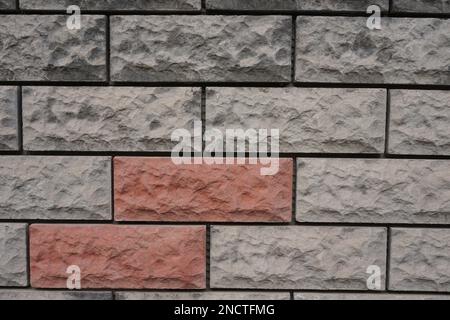 Wand aus grauen und orangefarbenen Steinen Stockfoto