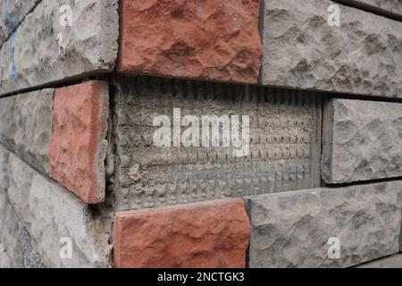 Eine Wand aus grauen und orangefarbenen Steinen mit einem fehlenden Stein Stockfoto