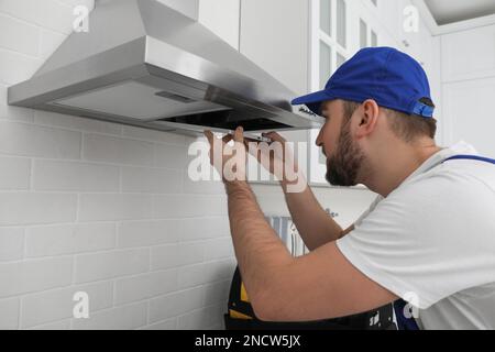 Arbeiter, der moderne Dunstabzugshaube in der Küche repariert Stockfoto