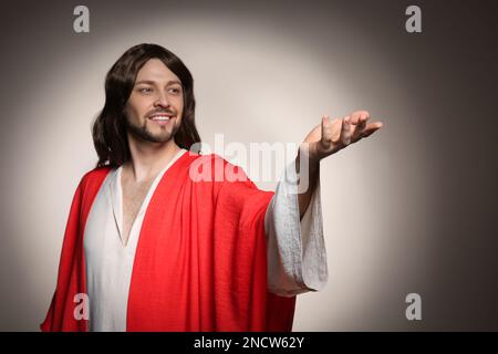 Jesus Christus streckt seine Hand auf beigefarbenem Hintergrund aus Stockfoto