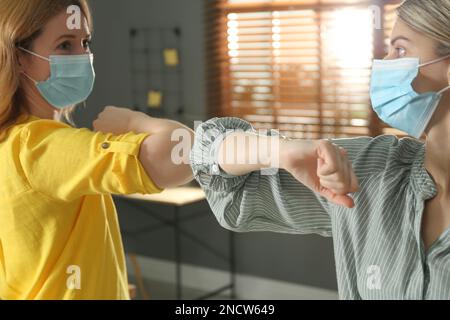Die Leute grüßen sich gegenseitig, indem sie Ellbogen statt Handschlag drinnen anstoßen, Nahaufnahme Stockfoto