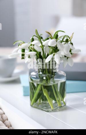 Wunderschöne Schneeglöckchen, Bücher und eine Tasse Kaffee auf dem Tablett im Schlafzimmer Stockfoto