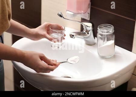 Eine Frau, die Backpulver benutzt, um den Abfluss im Bad zu reinigen, zu schließen Stockfoto
