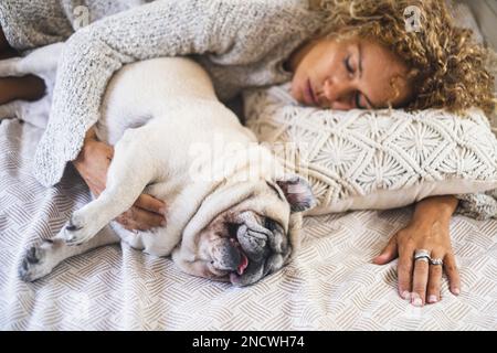 Hund und Leute schlafen zusammen im Bett mit Blick von oben. Konzept von Liebestier und bester Freund für immer. Eine Frau schläft mit dem Hündchen im Bett. Adorabl Stockfoto