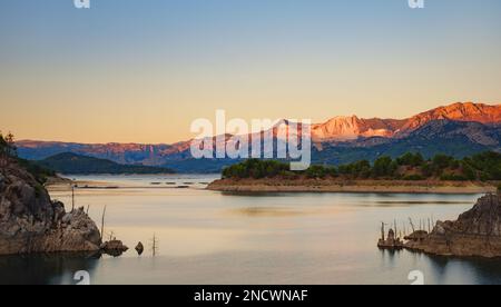 Reisen Sie durch die türkei, Burdur Region. Karacaoren-See und Berge bei Sonnenuntergang aus der Vogelperspektive in der Türkei. Waldinsel in türkisfarbener Wasserlandschaft Stockfoto