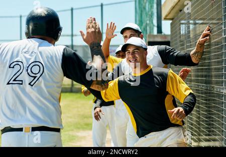 Wieder einmal waren die Gewinner. Eine Gruppe junger Baseballspieler jubelt, während sie tagsüber neben einem Baseballfeld standen. Stockfoto