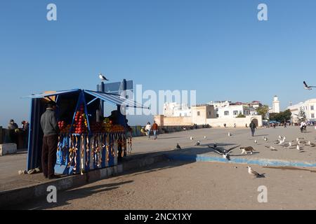 Ein kleiner Verkaufsstand, der frischen Fruchtsaft mit den Stadtmauern und der Medina der Altstadt von Essaouira in Marokko im Hintergrund verkauft Stockfoto