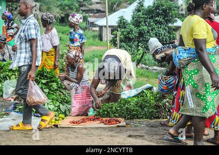 Einkaufen und Verkaufen auf dem geschäftigen Monrovia - Gbarnga Highway. Der Markt ist sehr geschäftig, und die Anbieter nehmen einen Teil der Straße ein, was zu starken Staus führt. Liberia. Stockfoto