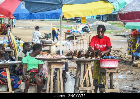 Einkaufen und Verkaufen auf dem geschäftigen Monrovia - Gbarnga Highway. Der Markt ist sehr geschäftig, und die Anbieter nehmen einen Teil der Straße ein, was zu starken Staus führt. Liberia. Stockfoto