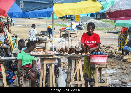 Einkaufen und Verkaufen auf dem geschäftigen Monrovia - Gbarnga Highway. Der Markt ist sehr geschäftig, und die Anbieter nehmen einen Teil der Straße ein, was zu starken Staus führt. Liberia. Stockfoto